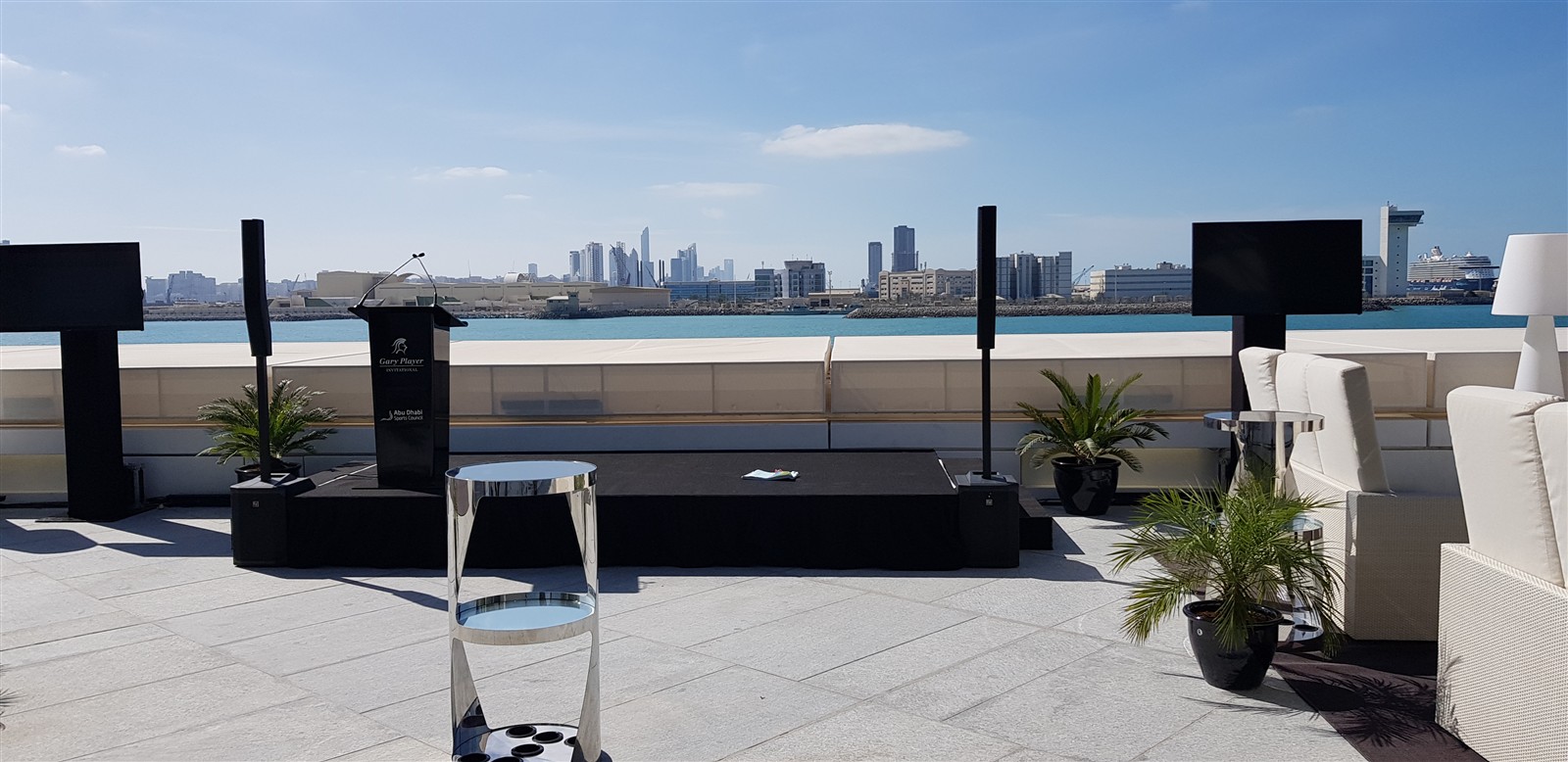 Column speakers and a lectern at a waterfront outdoor event